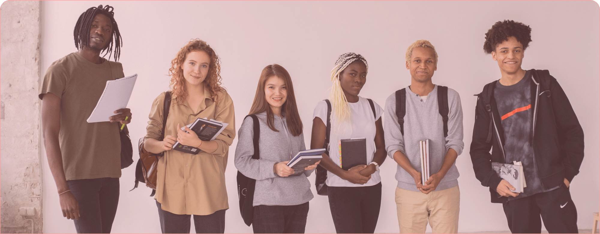 Group of six diverse students standing in a row, holding books and notebooks, with backpacks, against a plain background.